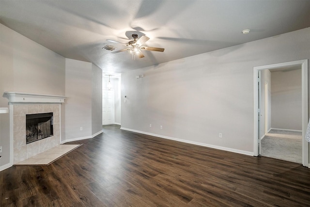 unfurnished living room featuring ceiling fan, dark wood-type flooring, and a tile fireplace