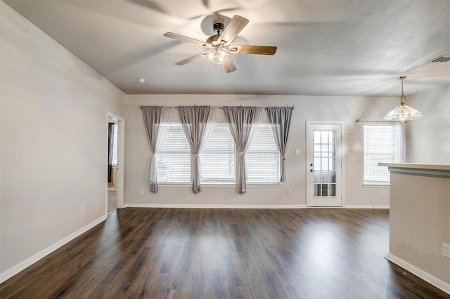 unfurnished living room with ceiling fan, dark hardwood / wood-style floors, and a textured ceiling