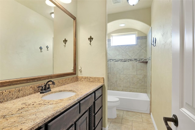 full bathroom featuring tile patterned flooring, vanity, tiled shower / bath, and toilet