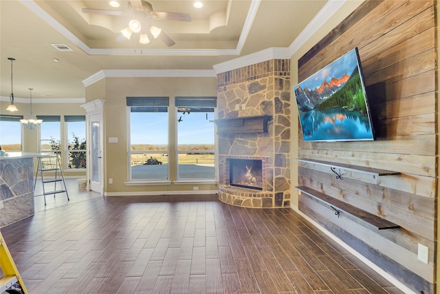 unfurnished living room with dark hardwood / wood-style flooring, a stone fireplace, crown molding, and a healthy amount of sunlight