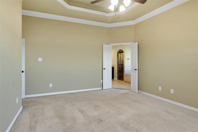 carpeted spare room with crown molding, a towering ceiling, ceiling fan, and a tray ceiling