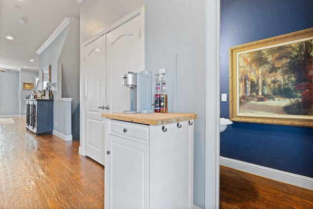 interior space featuring wooden counters, white cabinets, crown molding, and light hardwood / wood-style floors