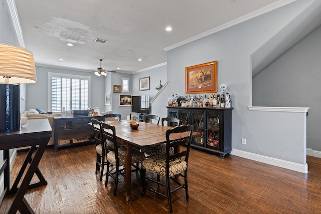 dining space featuring bar area, dark hardwood / wood-style floors, ceiling fan, and ornamental molding