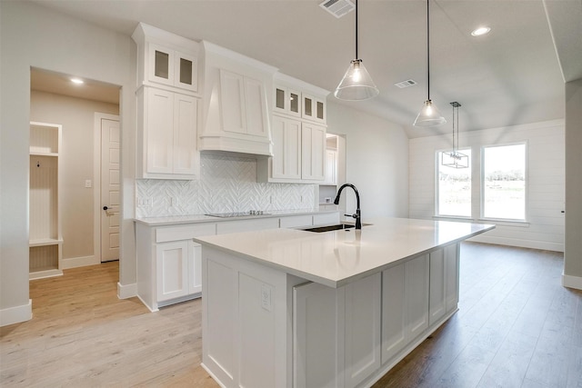 kitchen with sink, black electric stovetop, pendant lighting, a center island with sink, and white cabinets