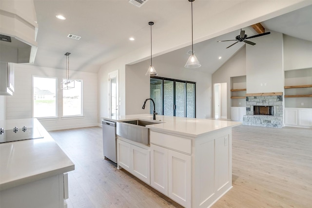 kitchen featuring stainless steel dishwasher, sink, white cabinetry, hanging light fixtures, and an island with sink