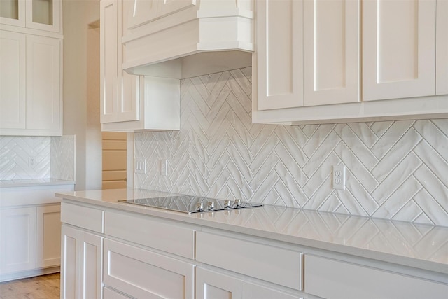 kitchen featuring backsplash, black electric cooktop, white cabinetry, and custom exhaust hood