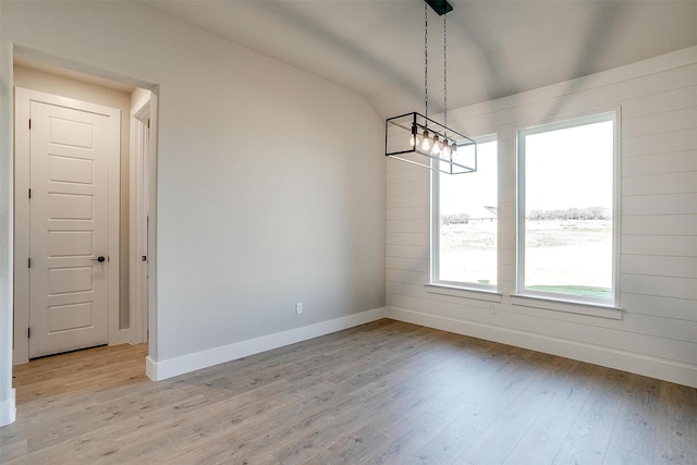 unfurnished dining area featuring light hardwood / wood-style flooring and vaulted ceiling