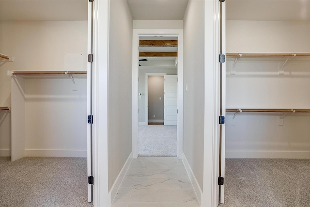 walk in closet featuring beam ceiling and light colored carpet