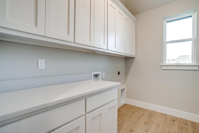 laundry area featuring electric dryer hookup, washer hookup, cabinets, and light wood-type flooring