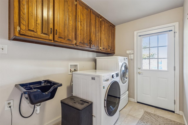 clothes washing area featuring washer and dryer, cabinets, and light tile patterned flooring