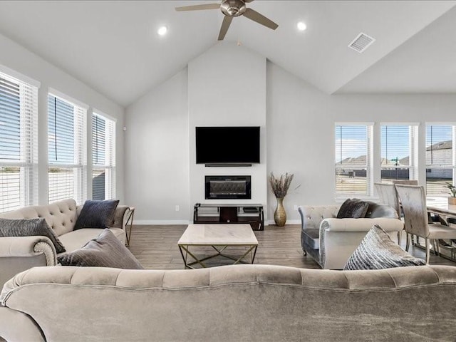 living room featuring hardwood / wood-style floors, ceiling fan, lofted ceiling, and a fireplace