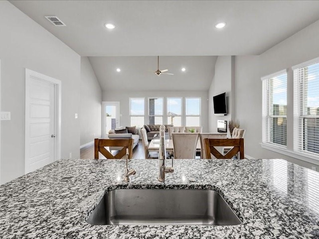 kitchen featuring a wealth of natural light, stone counters, sink, and ceiling fan