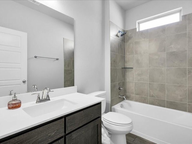 full bathroom featuring hardwood / wood-style floors, tiled shower / bath combo, toilet, and vanity