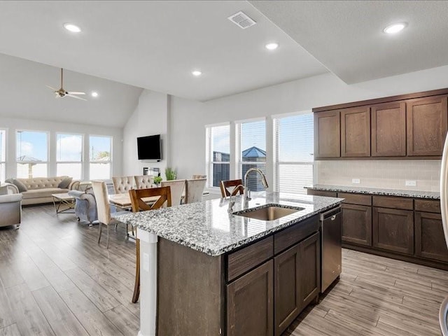 kitchen with a kitchen island with sink, sink, ceiling fan, light stone countertops, and light hardwood / wood-style floors