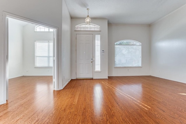 foyer entrance with ornamental molding, a wealth of natural light, and light hardwood / wood-style flooring