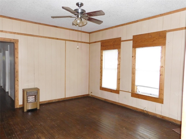 spare room featuring ceiling fan, ornamental molding, a textured ceiling, dark hardwood / wood-style flooring, and heating unit