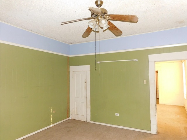 spare room featuring ceiling fan, light colored carpet, and a textured ceiling