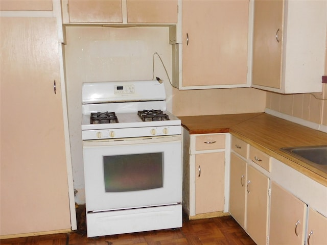 kitchen with tasteful backsplash, white gas range, dark parquet flooring, and butcher block counters