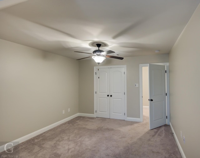 unfurnished bedroom featuring light carpet, baseboards, a closet, and a ceiling fan