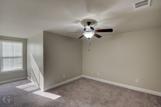 carpeted empty room featuring visible vents, baseboards, and ceiling fan