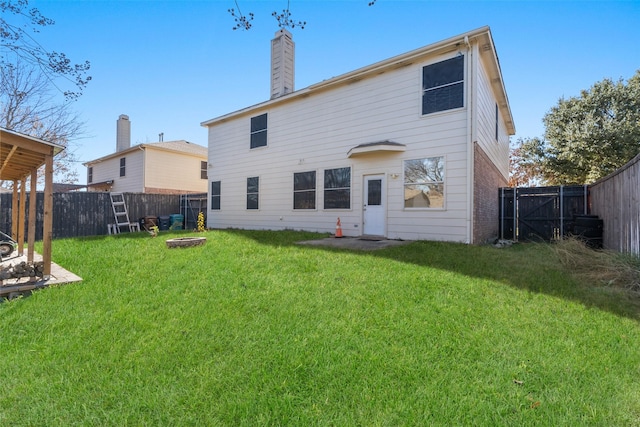 back of house featuring an outdoor fire pit and a lawn