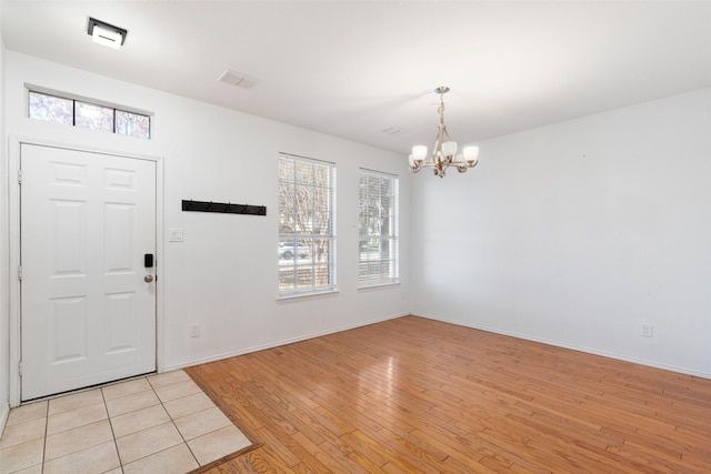 entryway with light hardwood / wood-style floors and a notable chandelier