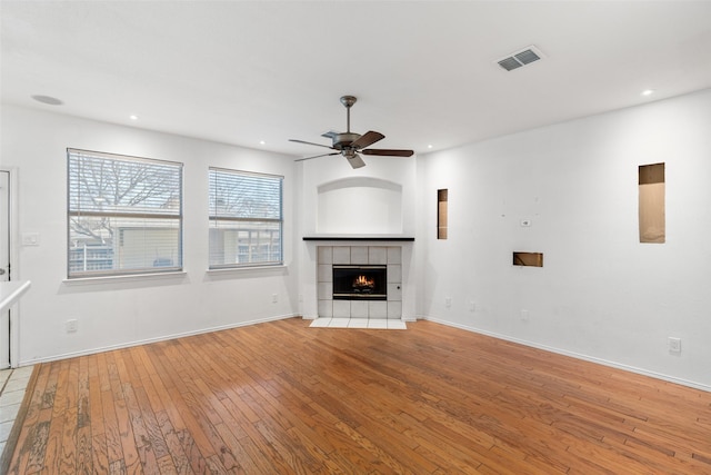 unfurnished living room featuring ceiling fan, light wood-type flooring, and a fireplace