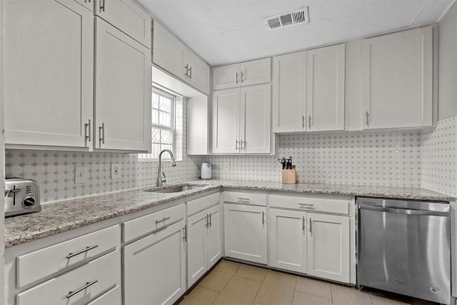 kitchen featuring dishwasher, sink, light stone countertops, tasteful backsplash, and white cabinetry