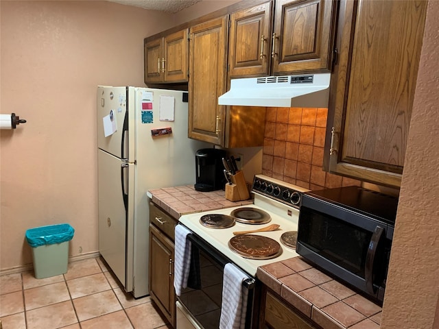 kitchen featuring tile countertops, light tile patterned flooring, and white appliances