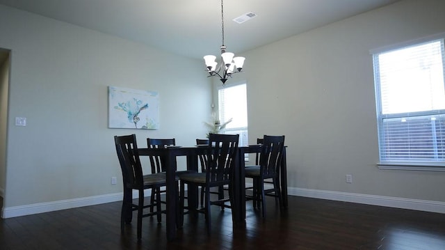 dining space with dark hardwood / wood-style floors and an inviting chandelier