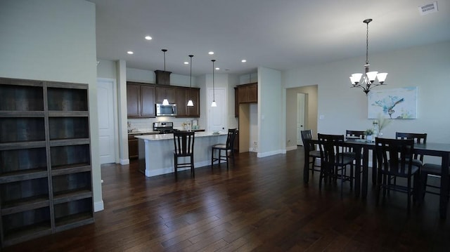 dining area featuring dark wood-type flooring and an inviting chandelier