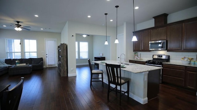 kitchen with ceiling fan, sink, hanging light fixtures, an island with sink, and appliances with stainless steel finishes