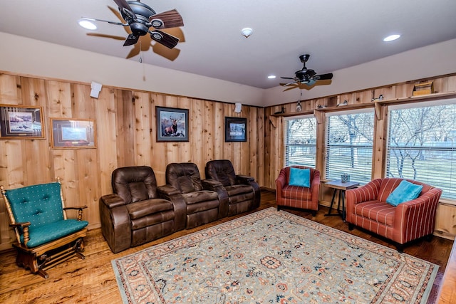 cinema featuring ceiling fan, wooden walls, and hardwood / wood-style floors