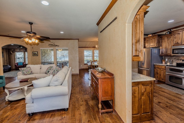 living room with crown molding, dark wood-type flooring, and ceiling fan