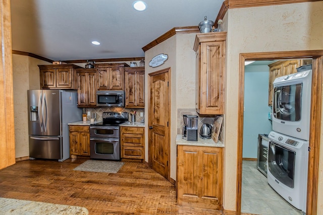 kitchen with crown molding, stacked washer and dryer, stainless steel appliances, and backsplash