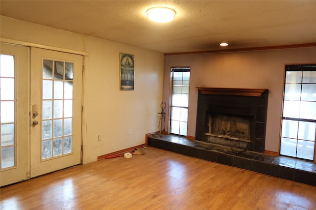 unfurnished living room with a tiled fireplace, light hardwood / wood-style flooring, and a textured ceiling