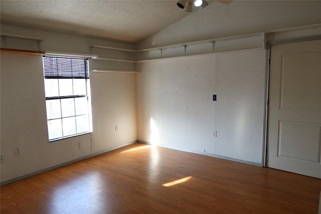 spare room featuring wood-type flooring and vaulted ceiling