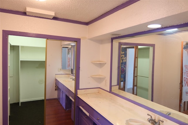 bathroom featuring hardwood / wood-style flooring, vanity, crown molding, and a textured ceiling