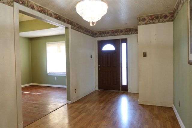 entrance foyer with an inviting chandelier, a textured ceiling, and hardwood / wood-style flooring