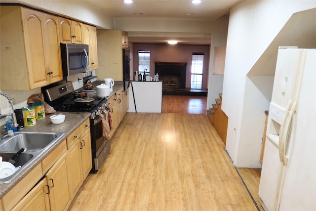 kitchen with sink, stainless steel appliances, light brown cabinetry, and light hardwood / wood-style flooring