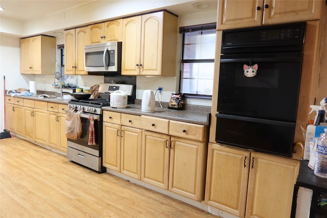 kitchen with light hardwood / wood-style flooring, stainless steel appliances, light brown cabinets, and sink