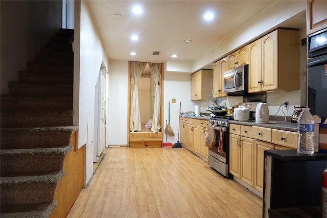 kitchen with light brown cabinets, light wood-type flooring, and appliances with stainless steel finishes