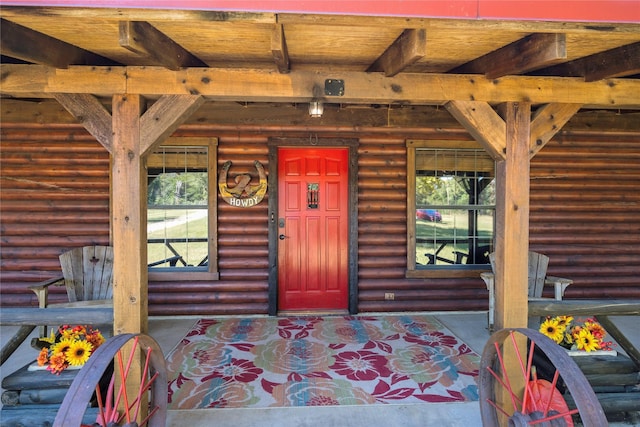 interior space with log walls, beamed ceiling, and wood ceiling