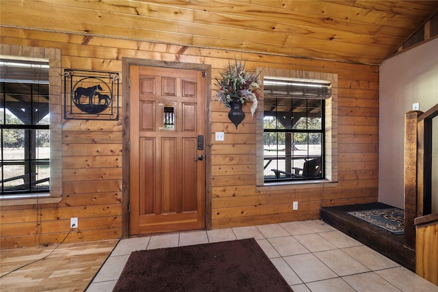 tiled foyer entrance featuring plenty of natural light, wood walls, and vaulted ceiling