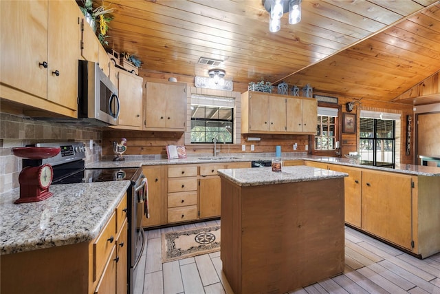 kitchen with a center island, stainless steel appliances, light stone counters, and sink