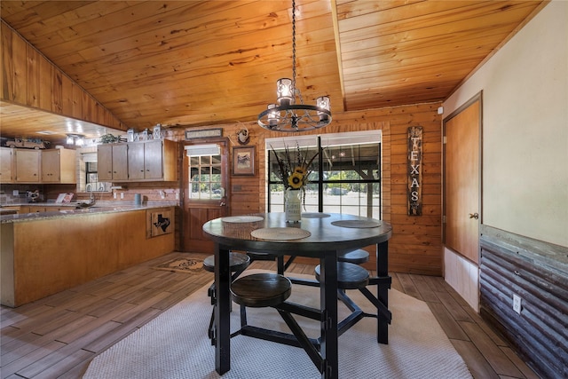 dining room featuring wooden walls, a healthy amount of sunlight, and lofted ceiling