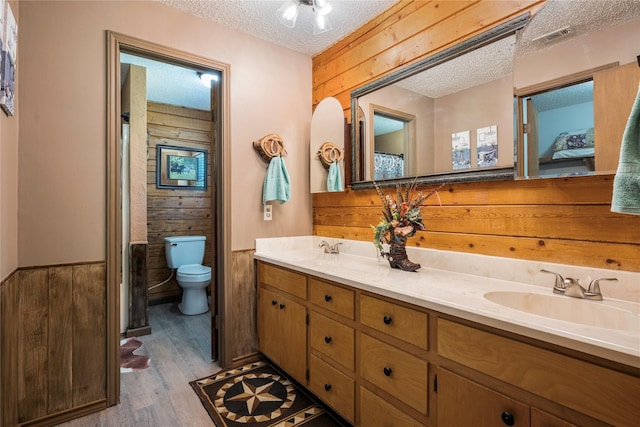 bathroom with wood walls, hardwood / wood-style floors, a textured ceiling, and toilet