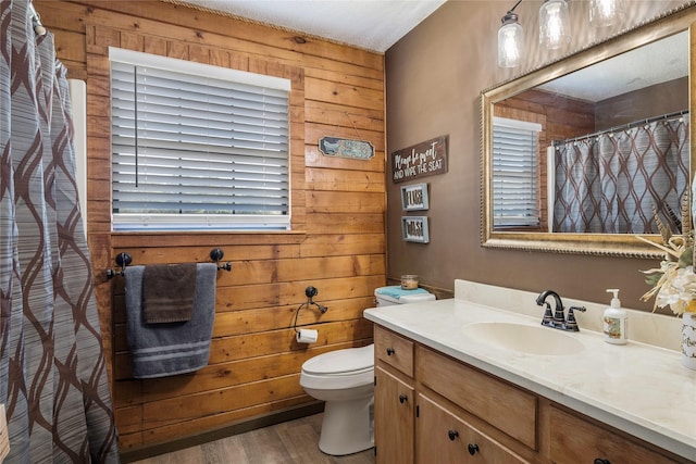 bathroom featuring wood-type flooring, vanity, toilet, and wooden walls