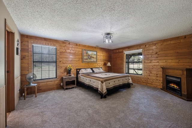 bedroom featuring wooden walls, carpet, and a textured ceiling