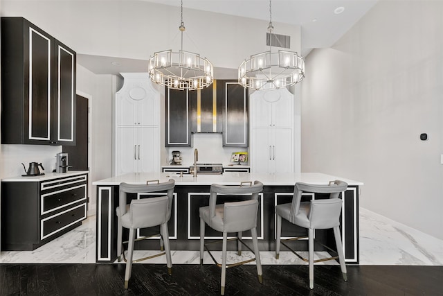 kitchen featuring decorative light fixtures, sink, a kitchen breakfast bar, a kitchen island with sink, and a chandelier